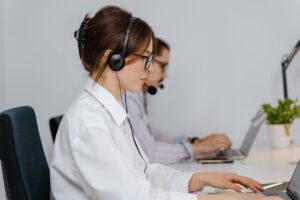 Customer service representatives working in a call center, wearing headsets and assisting clients through online support.