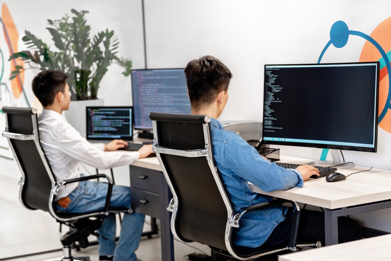 Two developers working on code at their desks in a modern software company.