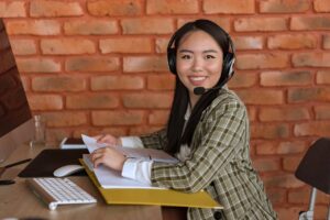 Filipina call center agent smiling at her desk with a headset in a BPO office.