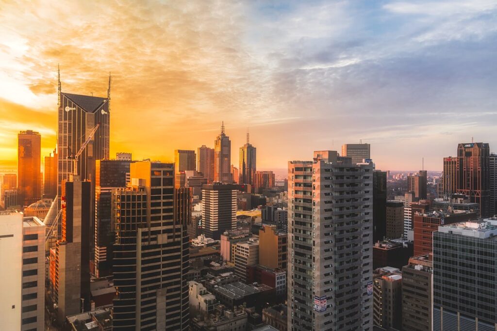 "A stunning cityscape of Melbourne, Australia, at sunset, featuring modern skyscrapers and golden hues reflecting off the buildings.