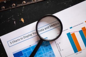 A magnifying glass placed over a printed data analysis report with bar charts and metrics, representing business insights.