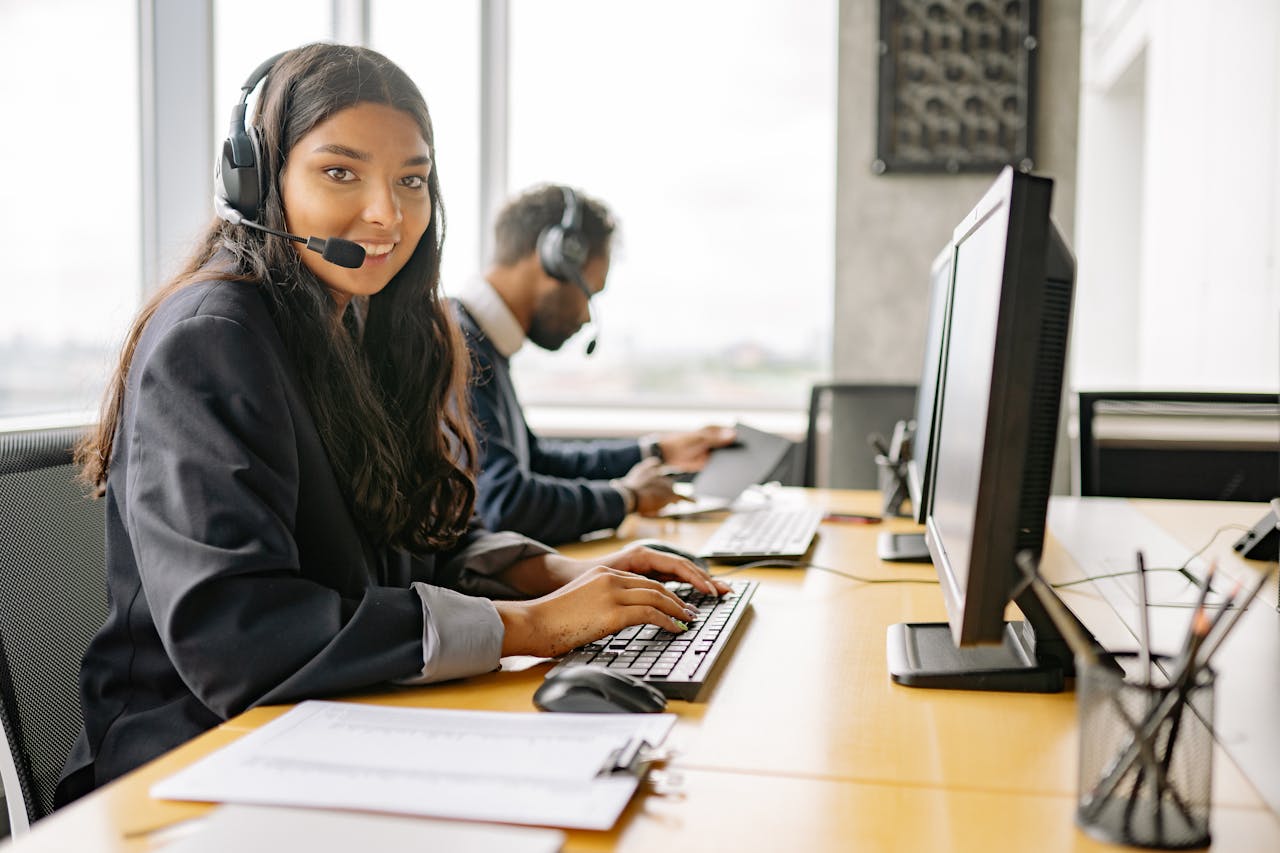 Female customer service representative typing on computer while wearing a headset in a BPO office.