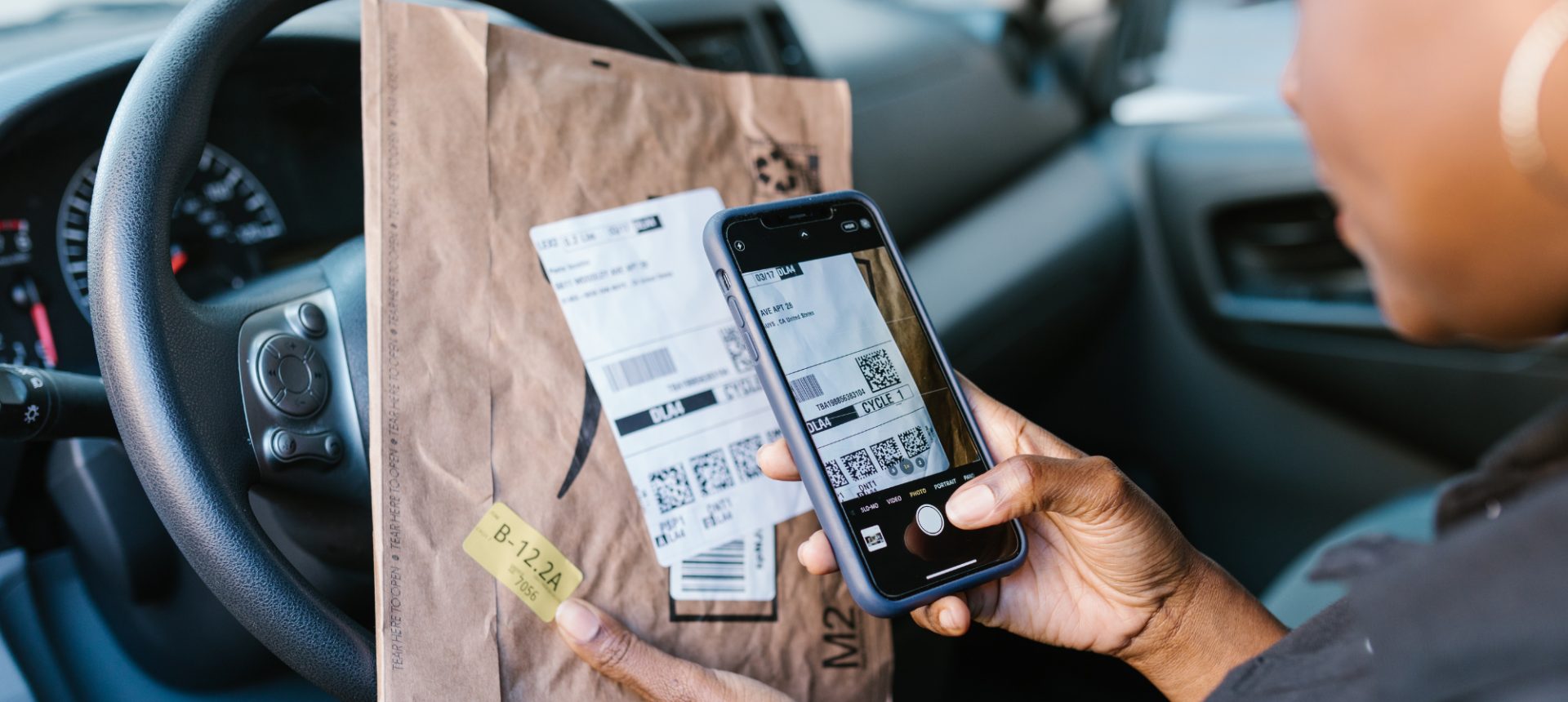 Driver scanning a parcel label with his phone, the hand-off a 3PL exception desk tracks