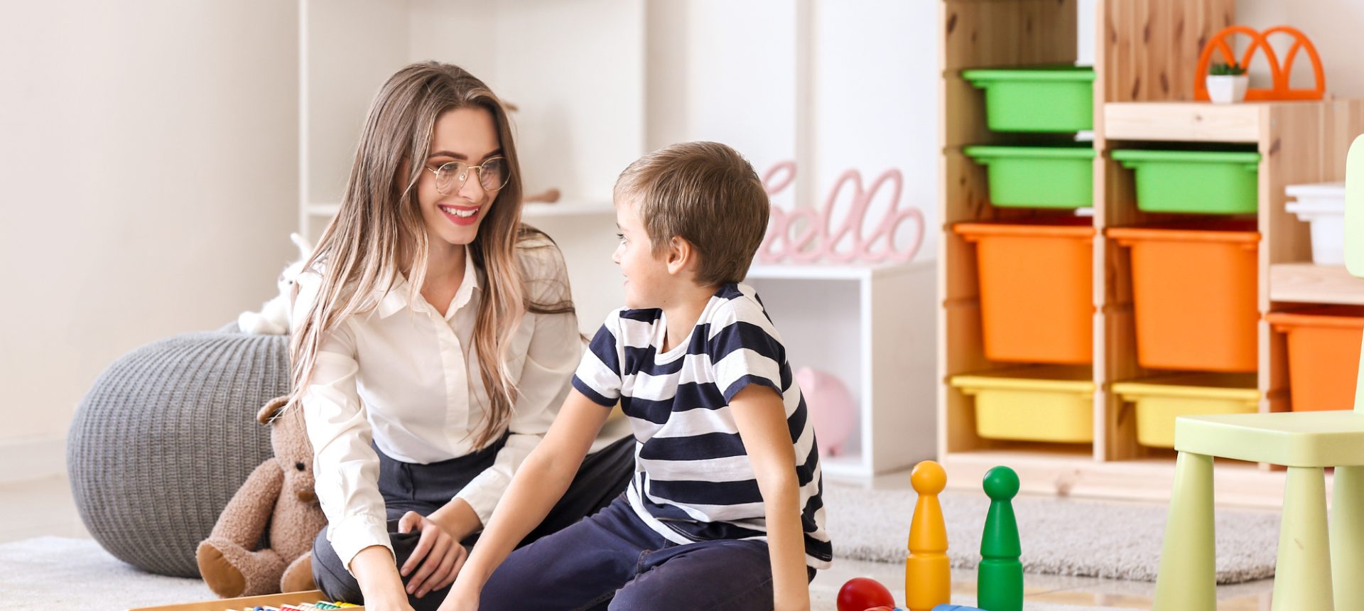 Therapist smiling with a young boy on a playroom floor during a session that ABA billing has to authorize