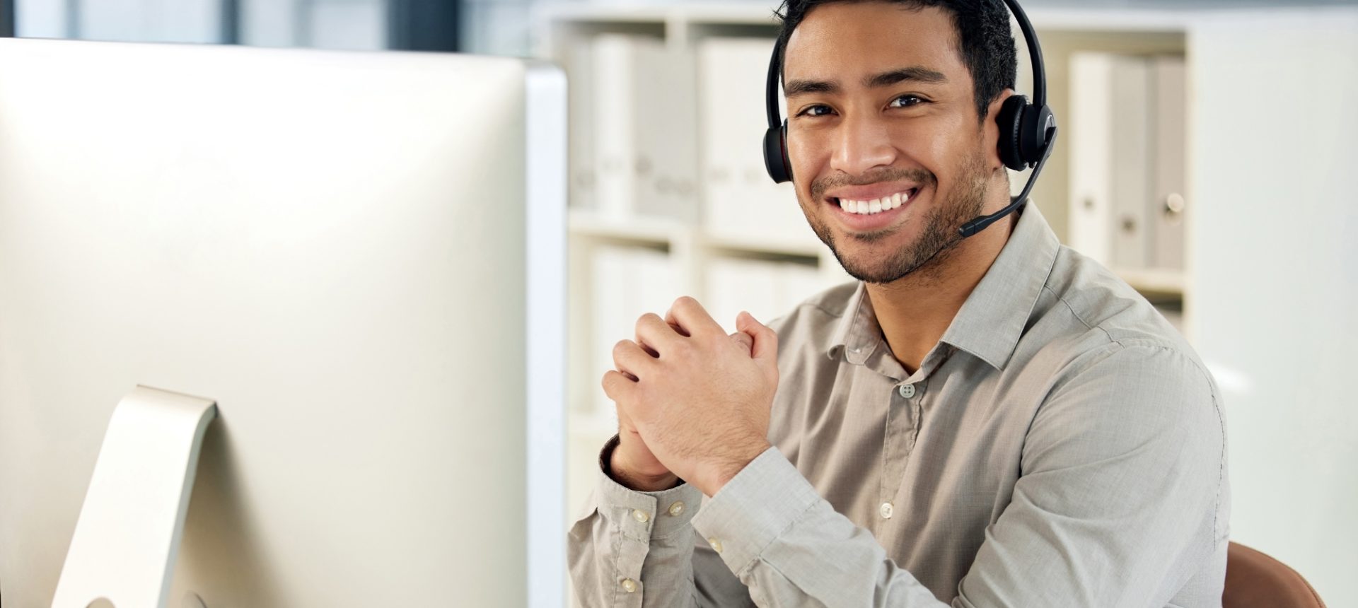 Smiling agent in a headset at his desk monitor, ready to answer an Amazon seller's account question