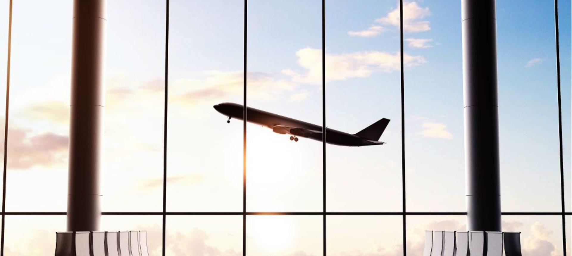 Passenger jet taking off beyond the windows of an empty airport departure lounge