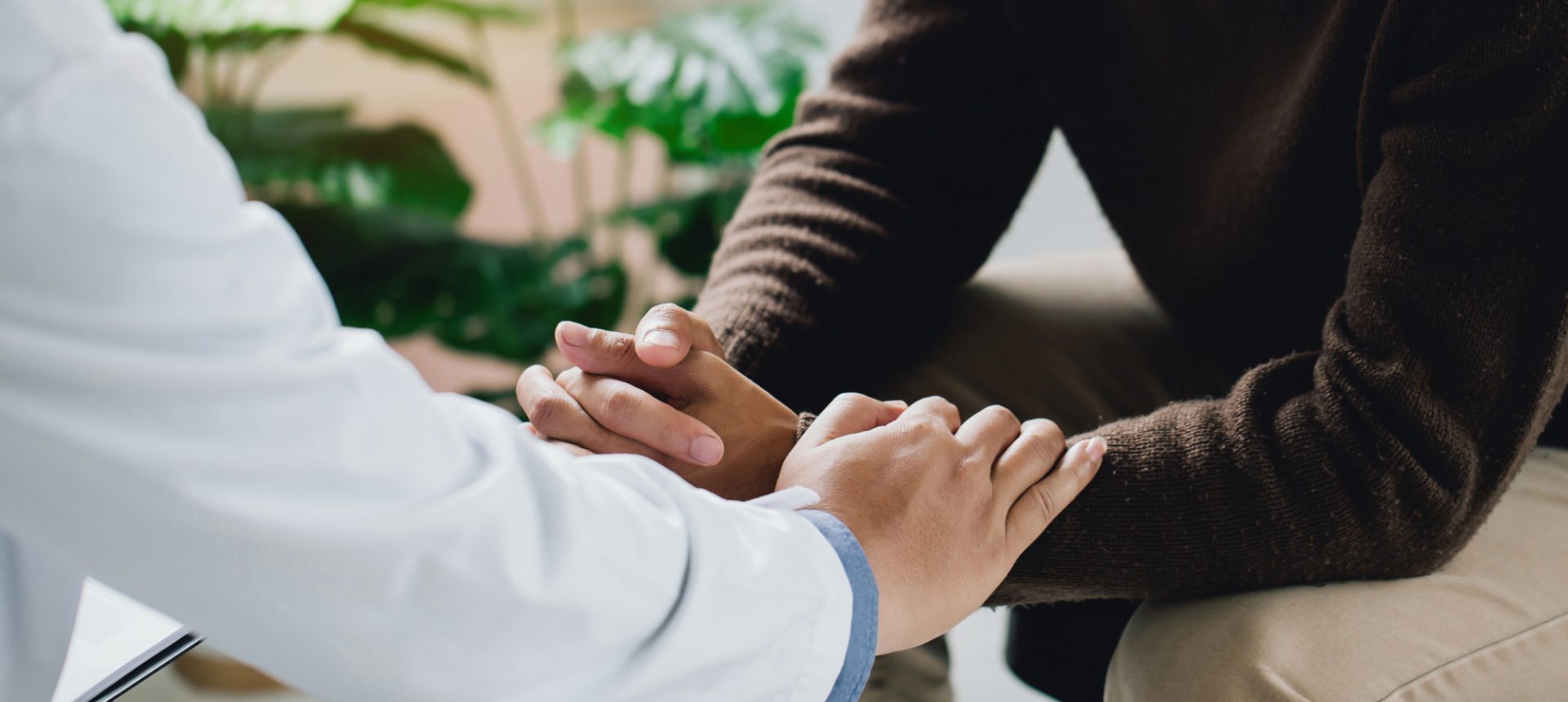 Clinician resting a hand on a patient's clasped hands in a therapy session that behavioral health billing must cover