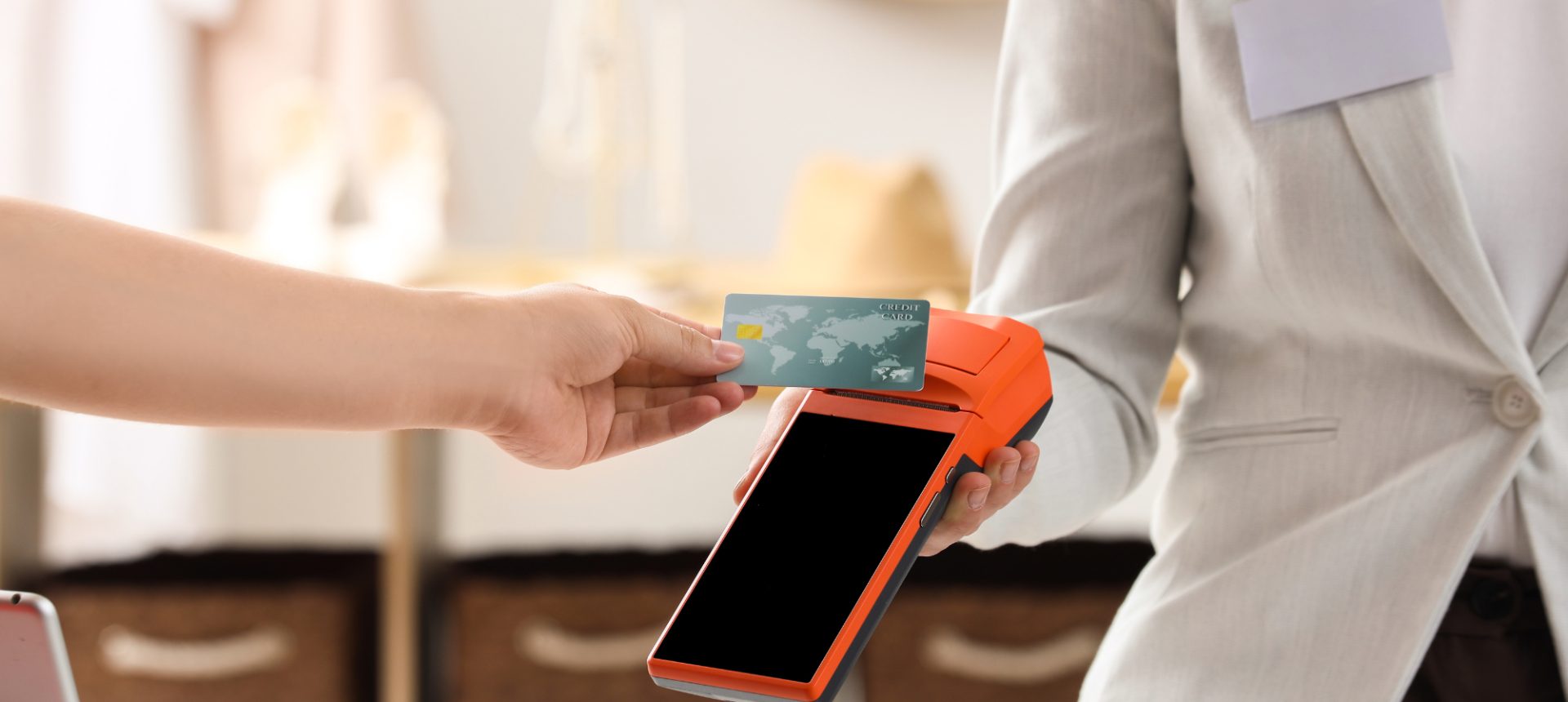 Customer holding a payment card to a handheld terminal at a shop counter, the purchase a card issuing team stands behind