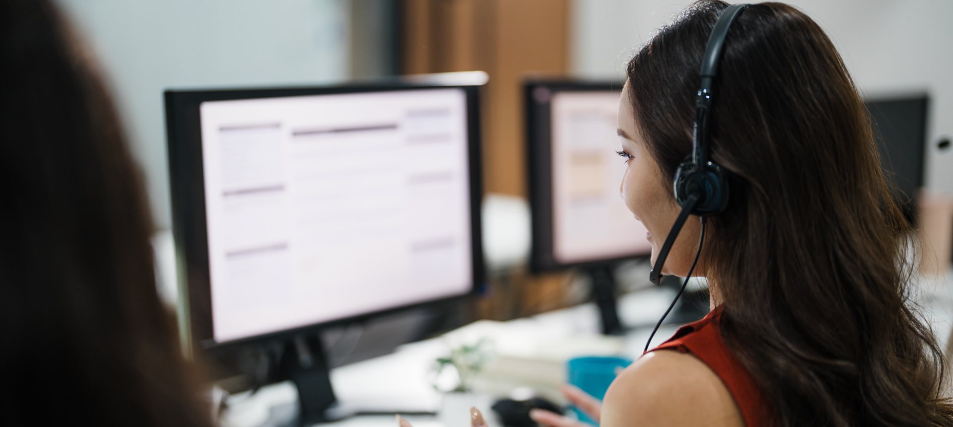 Collections agent with a headset speaking with a customer about an account at her workstation, representing collections outsourcing in the Philippines