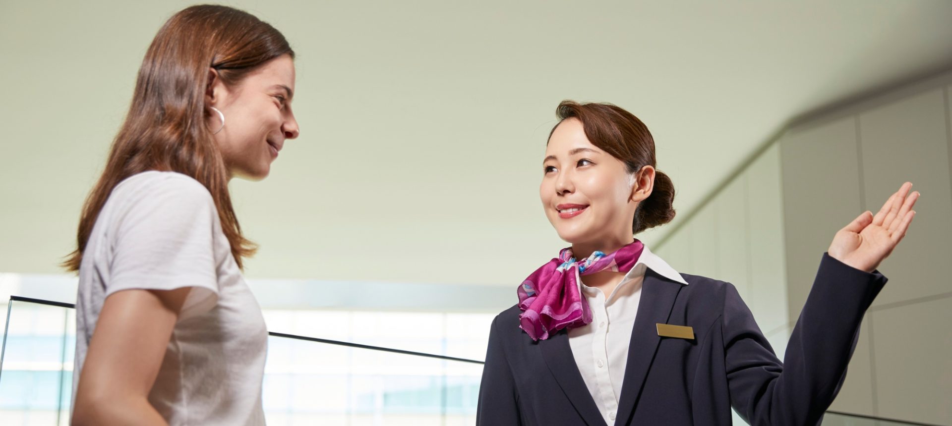 Uniformed host guiding a traveler with her suitcase, the welcome a cruise guest support desk extends before boarding