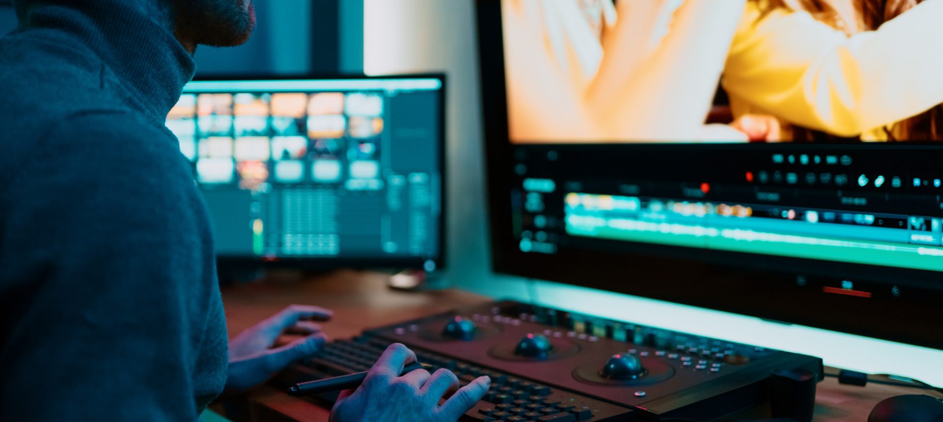 Video editor cutting footage on two screens at a color console, the lesson content an edtech operations team reviews