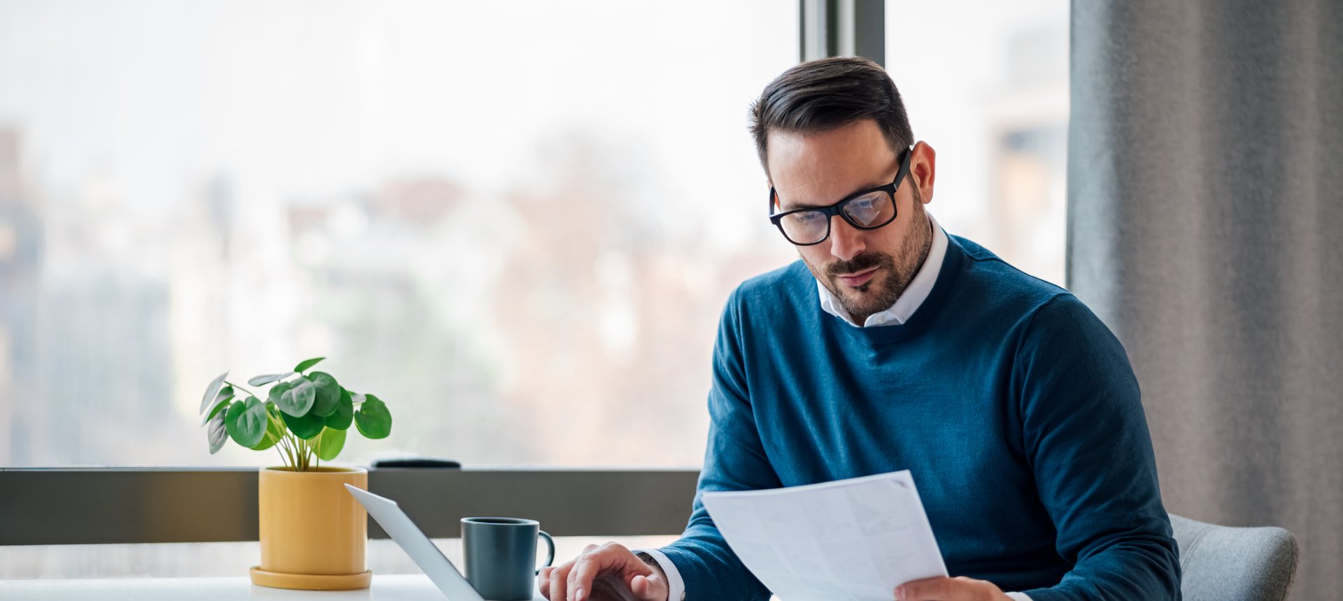 Financial data annotator in glasses reviewing a statement page before tagging its fields
