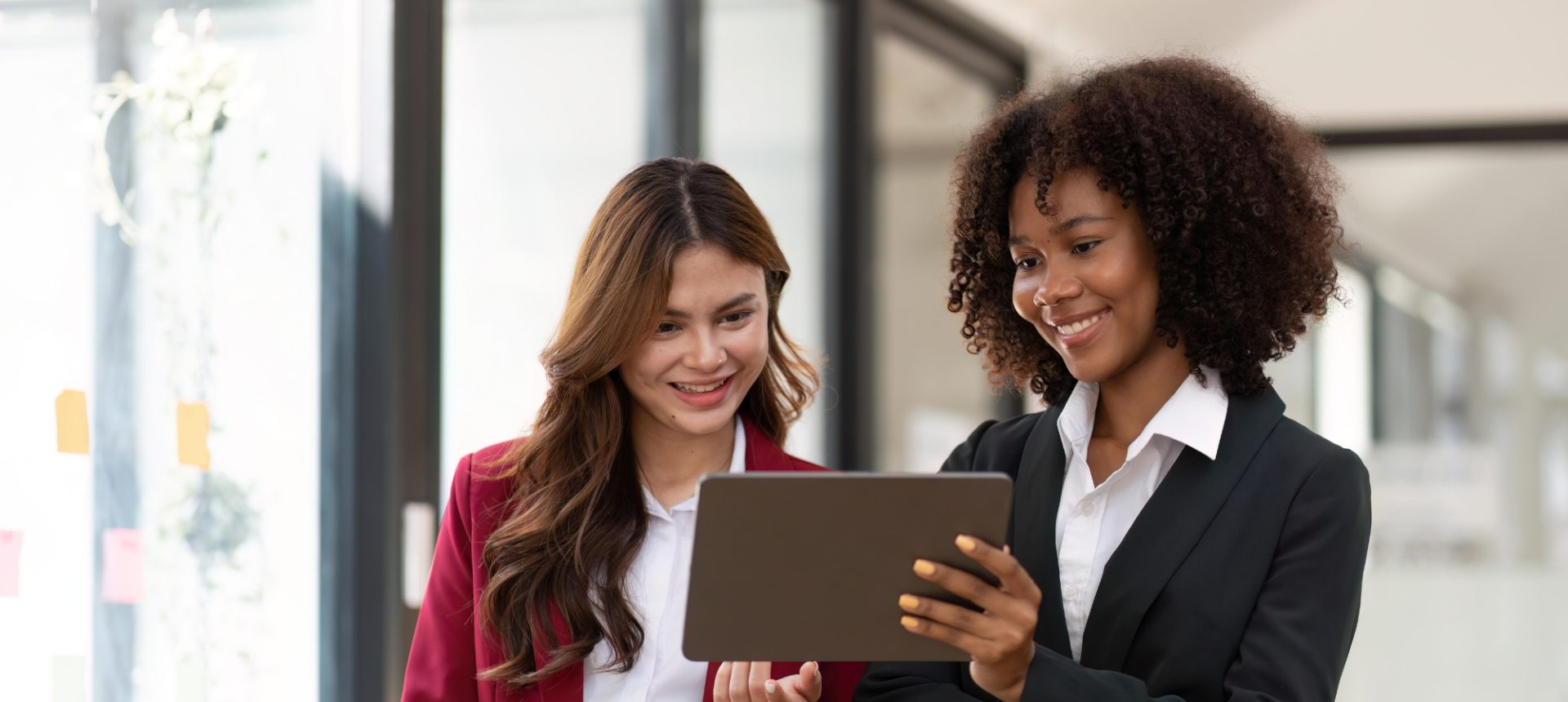 Two colleagues in business suits reviewing a customer case together on a tablet in a bright office