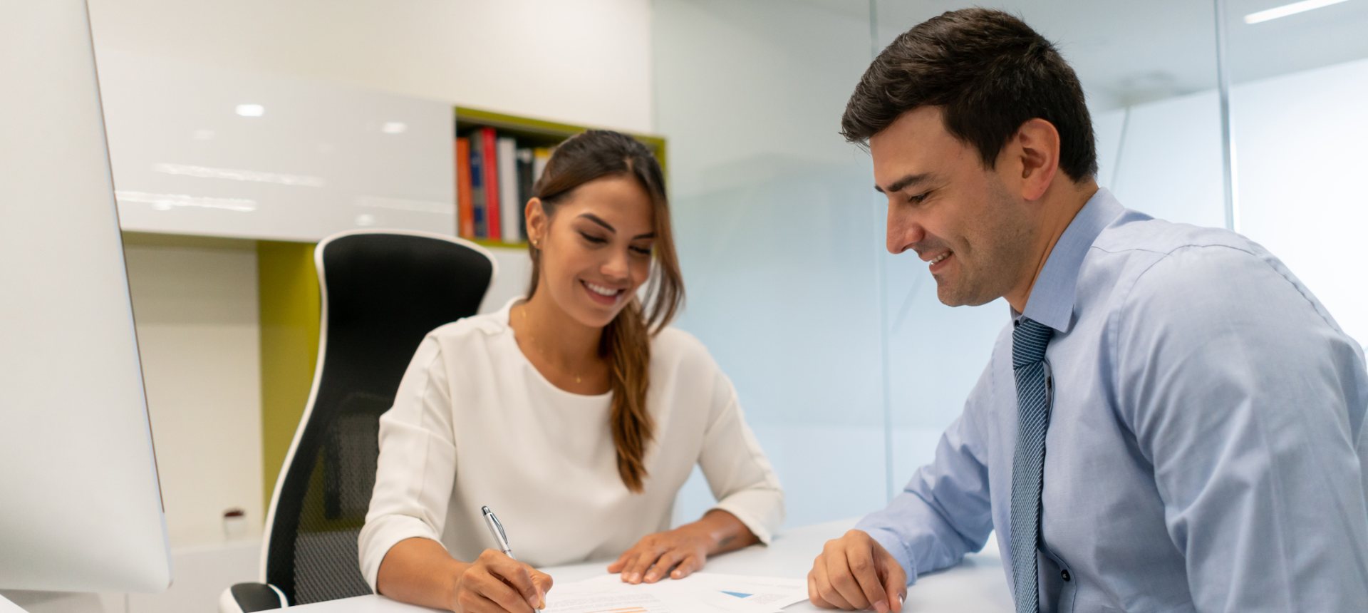Financial services advisor reviewing documents with a smiling client at an office desk, representing financial services outsourcing in the Philippines