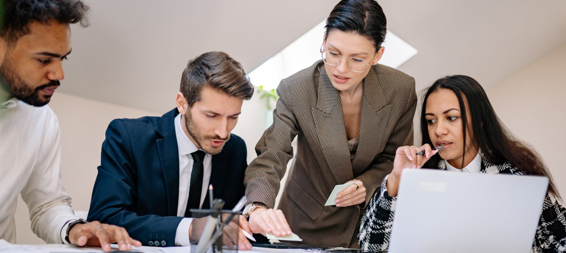 Four colleagues working through paperwork and a laptop at one table, the documents a brokerage back office closes