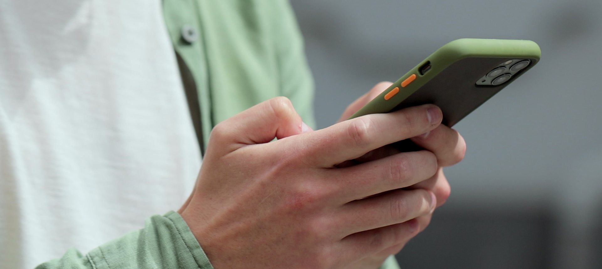 Close-up of hands typing a message on a smartphone, the conversation an in-app messaging team answers