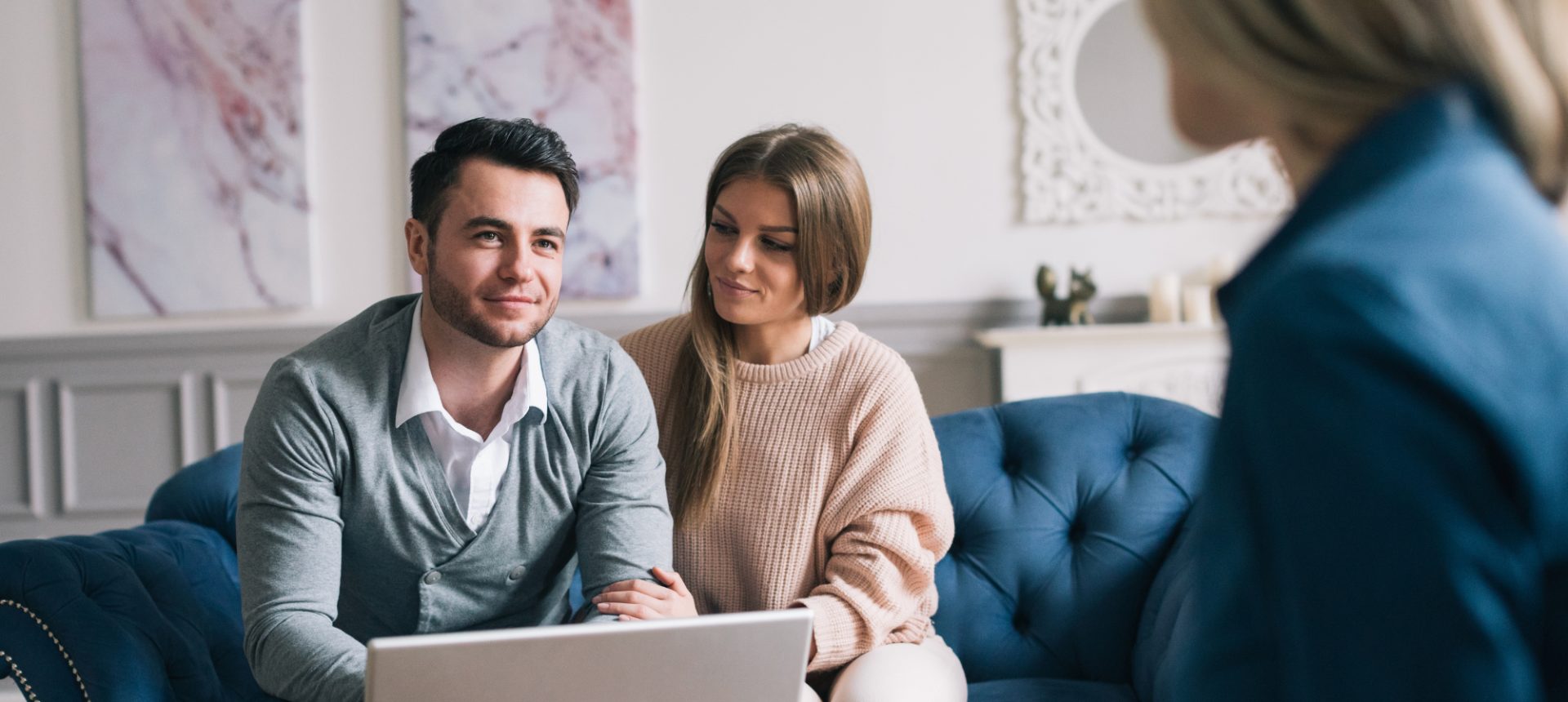Couple on a sofa answering an underwriter's questions over a laptop