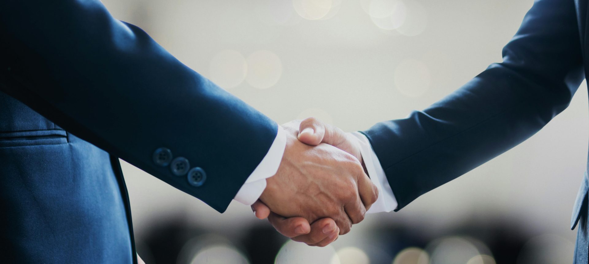 Two people in navy suits shaking hands on a settlement once the liens against it are resolved