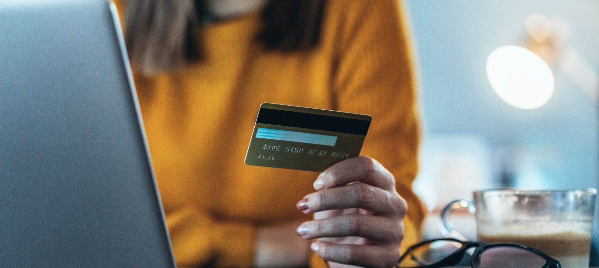 Customer holding a payment card beside a laptop, the transaction that payments reconciliation must match