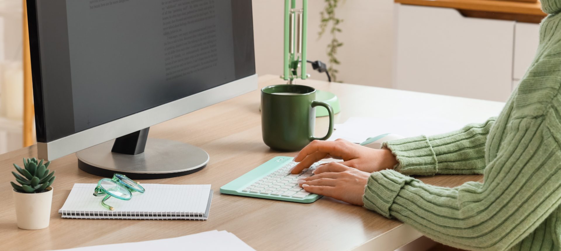 Editor typing at a desktop manuscript with a notebook and coffee mug