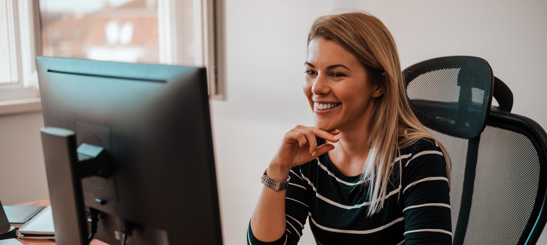 Smiling evaluator at her monitor ranking two model answers for a reward model