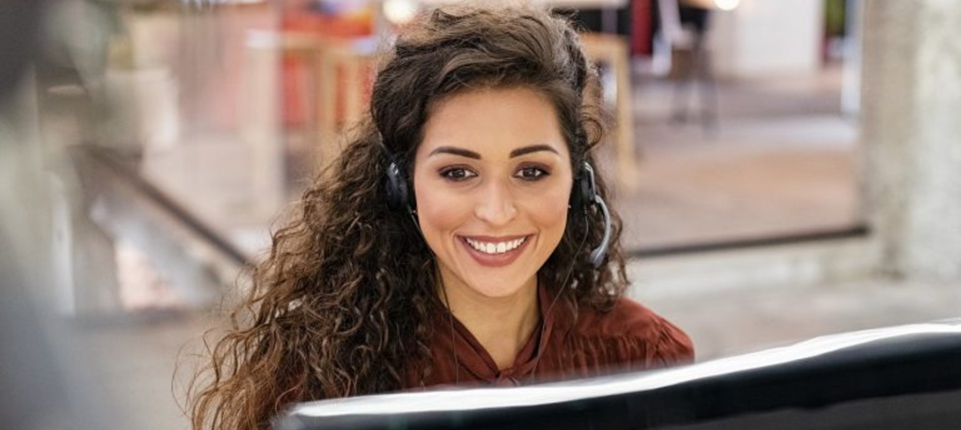 Smiling sales and lead generation agent with a headset calling prospects from her workstation, representing sales and lead generation outsourcing in the Philippines