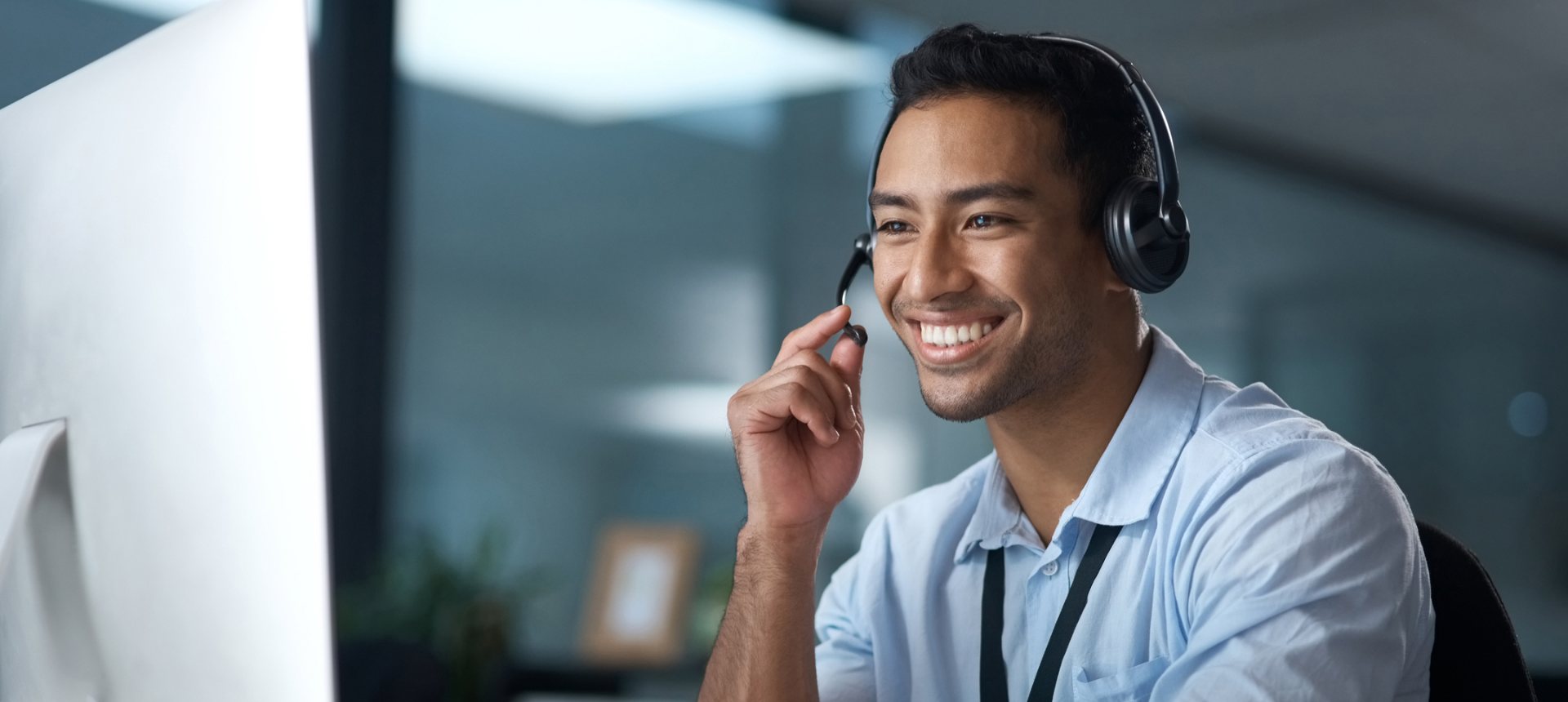 Smiling audio specialist with a headset at his workstation, labeling who spoke when in a recording