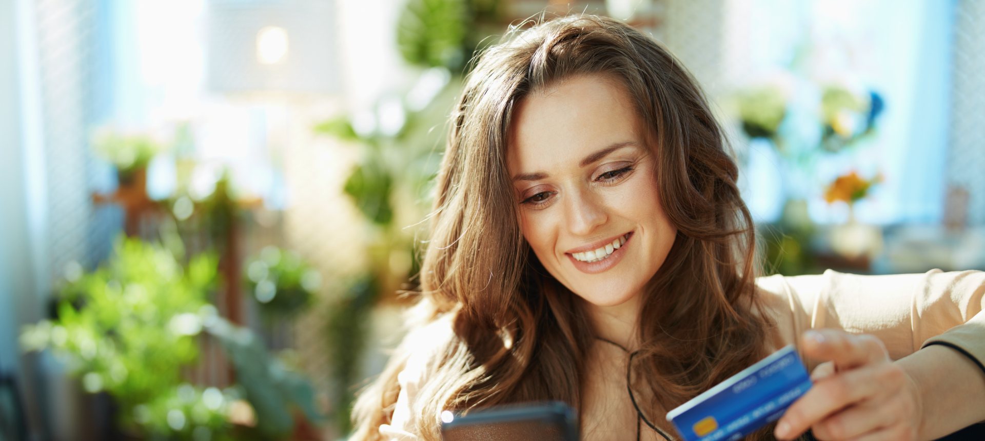 Smiling shopper with her phone and card, buying an item she found by photo search