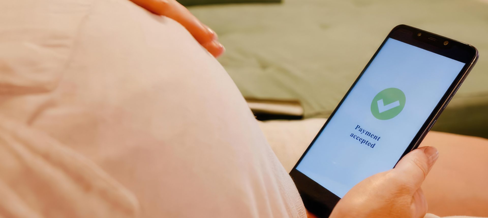 Shopper resting at home holding a phone that shows a payment accepted screen, an order a WhatsApp commerce team confirms