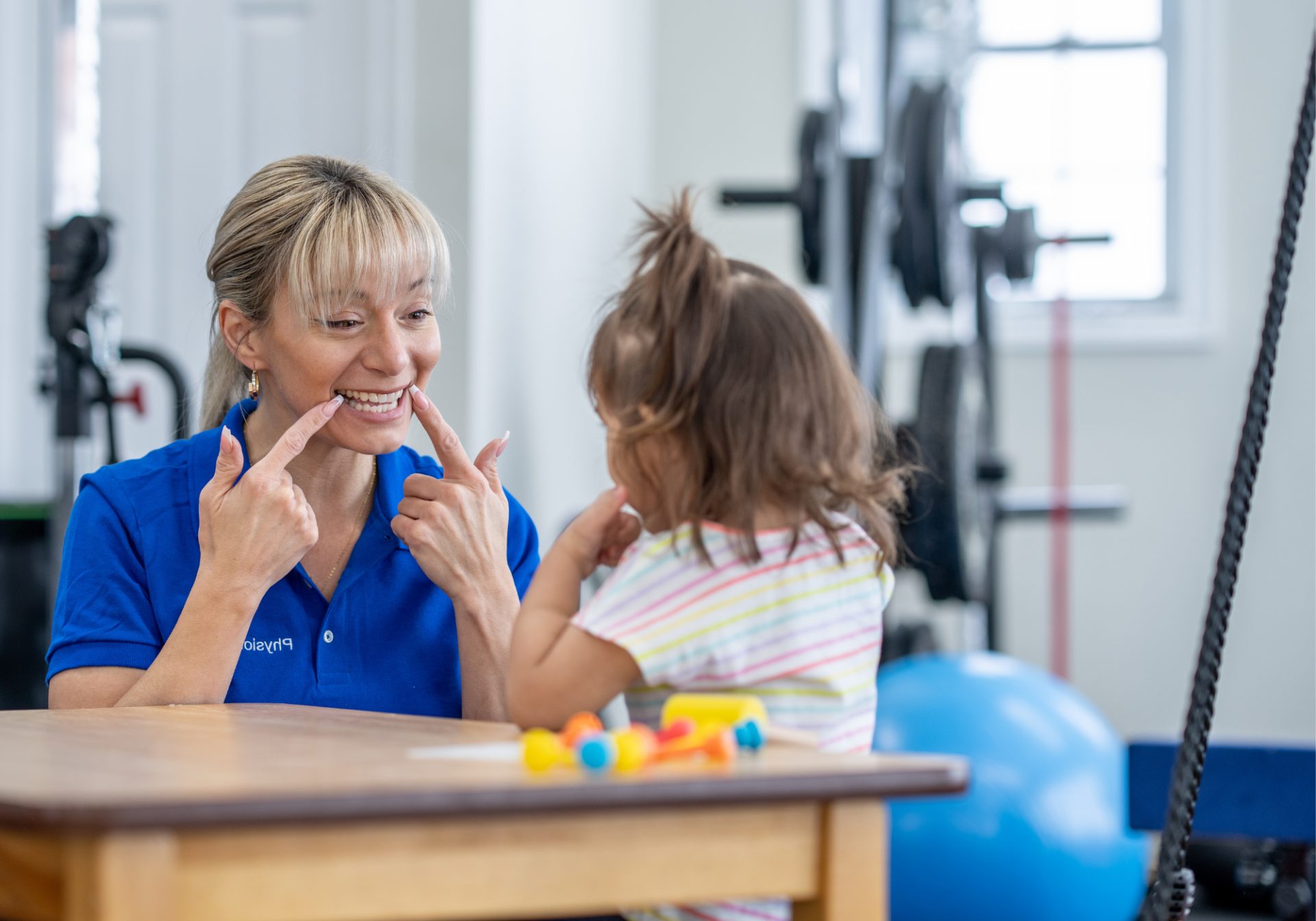 Therapist smiling with a young girl at a therapy table, for a post on ABA authorization tracking
