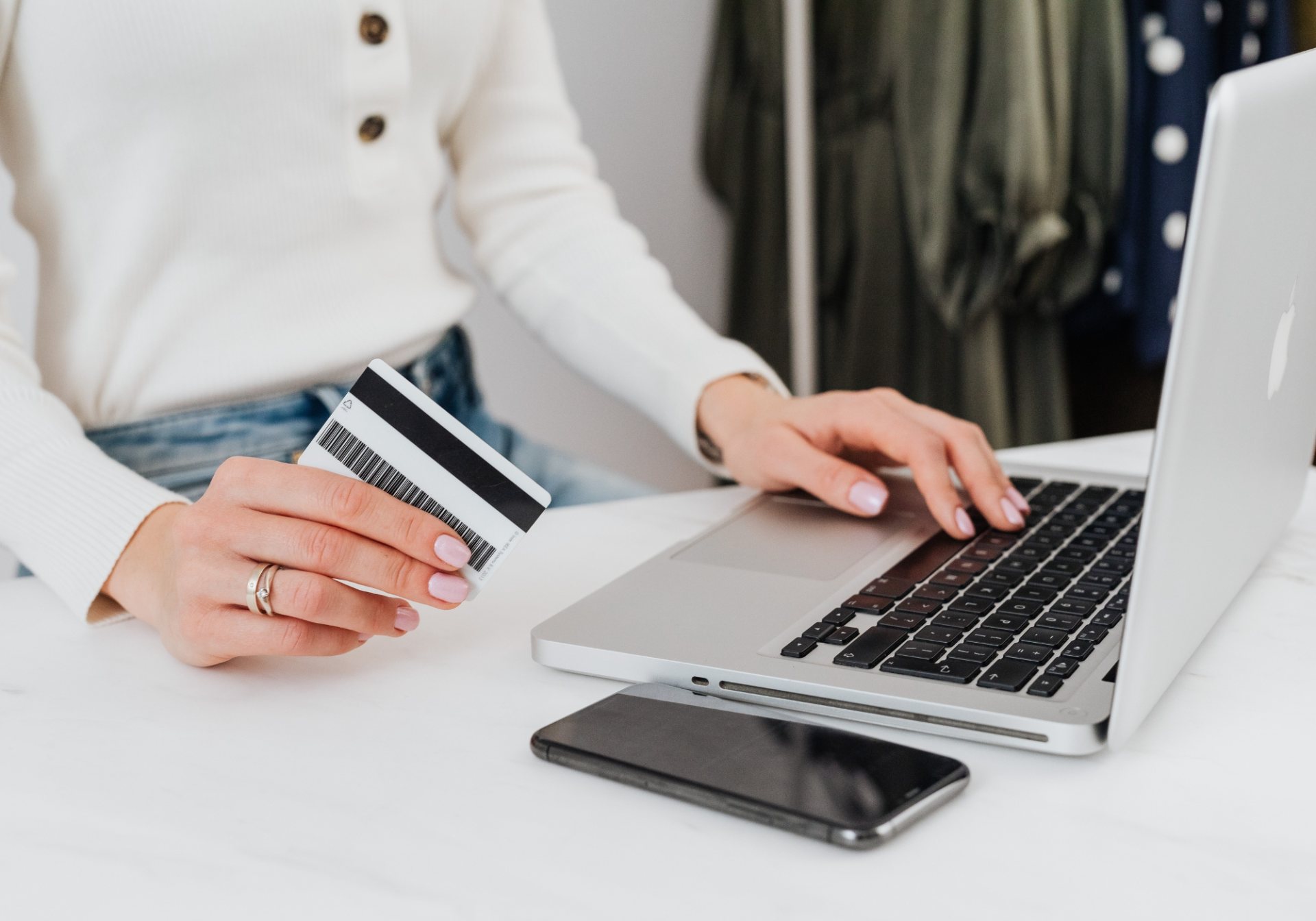 Cardholder holding a gold payment card in front of a laptop, the card a card issuing program supports
