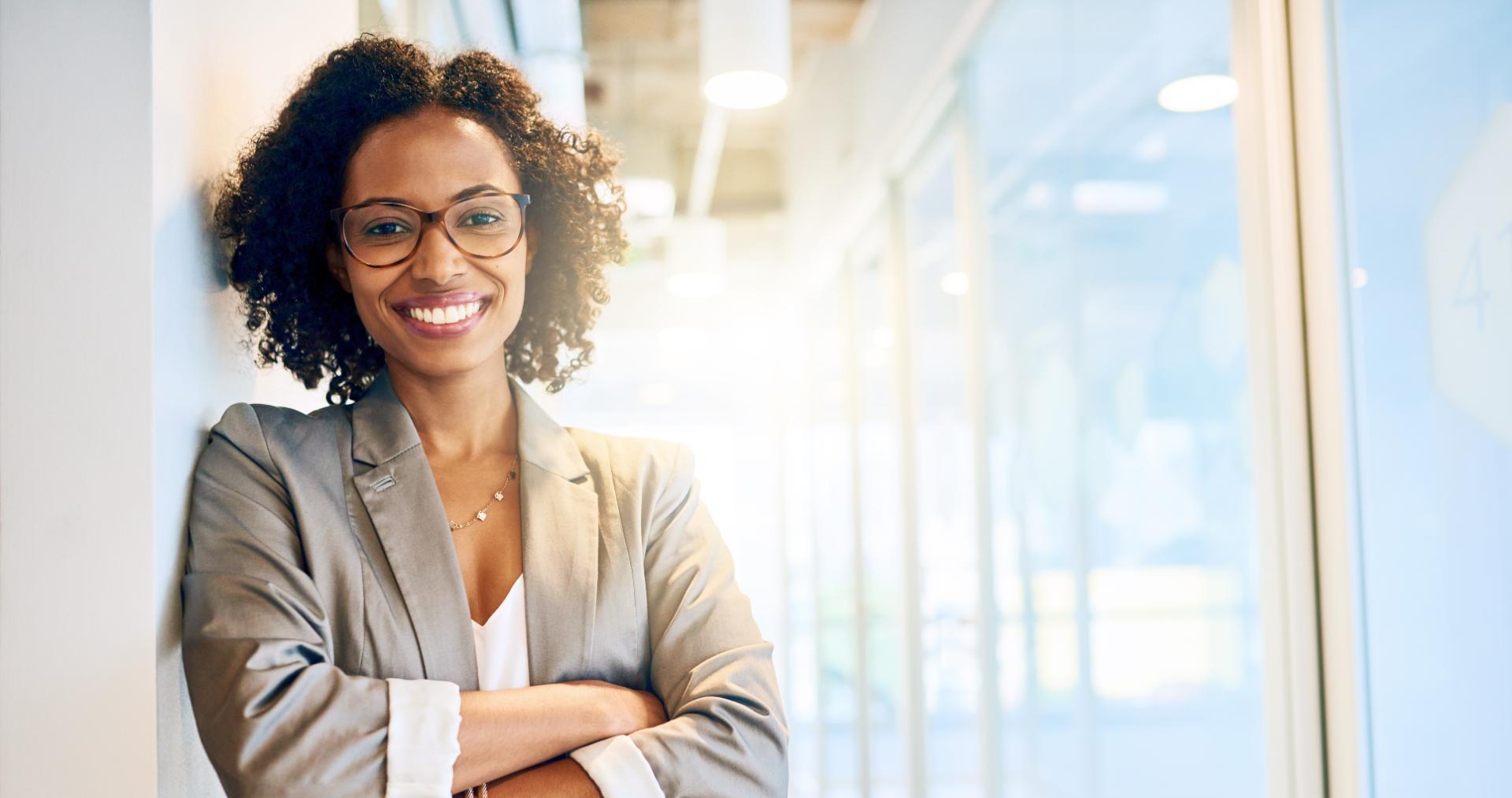 Smiling PITON-Global outsourcing advisor with arms crossed in a bright office corridor, ready to help buyers get a free vendor shortlist for outsourcing to the Philippines