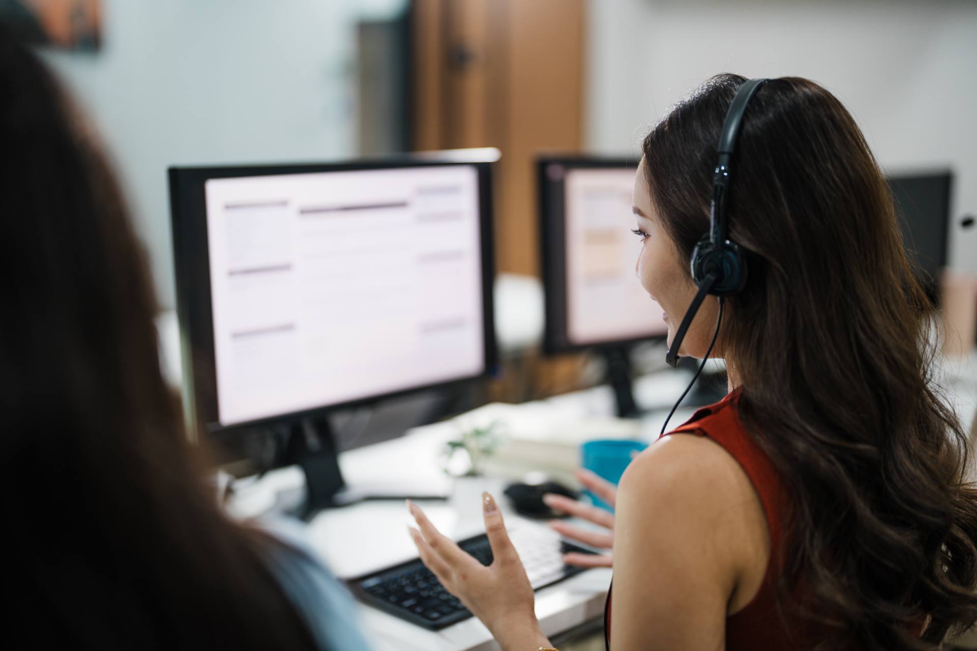 Content moderator with headset reviewing flagged content on dual monitors at a Philippine BPO