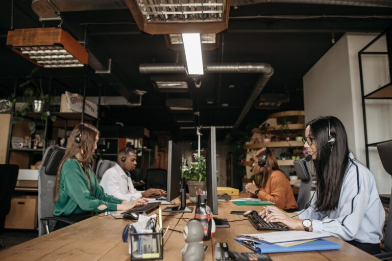Team with headsets validating CRM records at shared workstations, for a post on CRM data decay