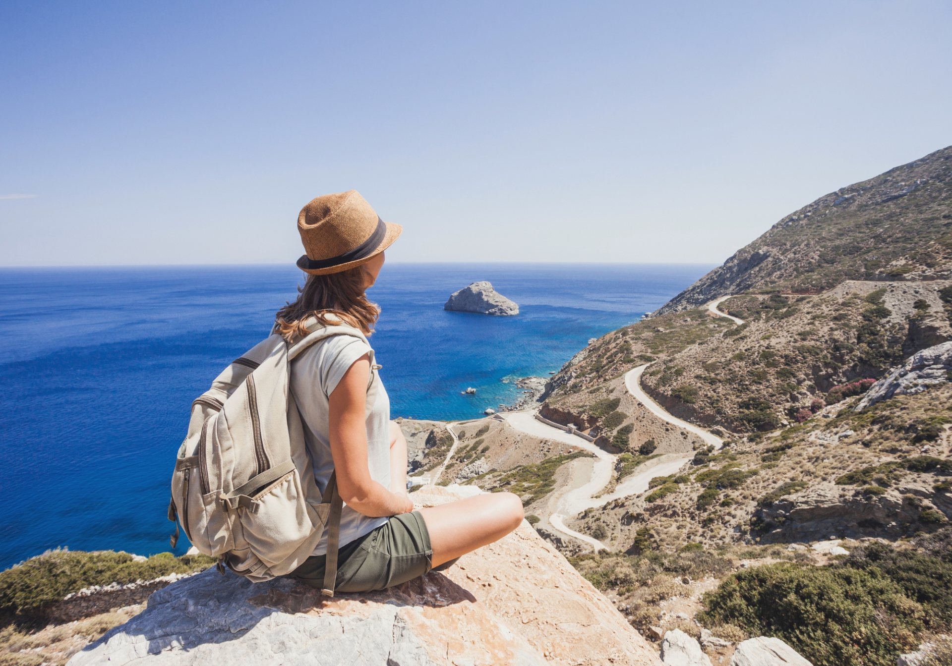 Traveler in a sun hat overlooking a coastal road, the ground experience a DMC arranges