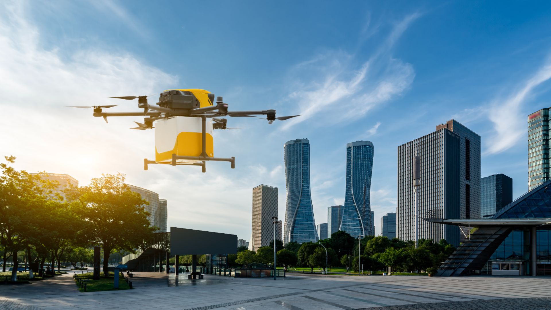 Yellow delivery drone carrying a parcel over a city plaza with high-rise towers behind it, representing drone operations outsourcing to the Philippines