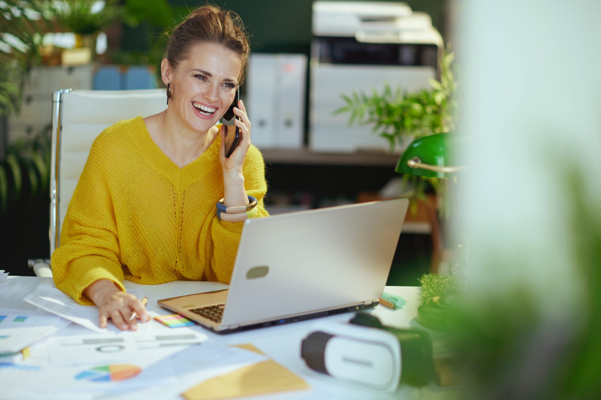 Smiling customer support professional on a phone call at her laptop in a bright office, representing call center outsourcing