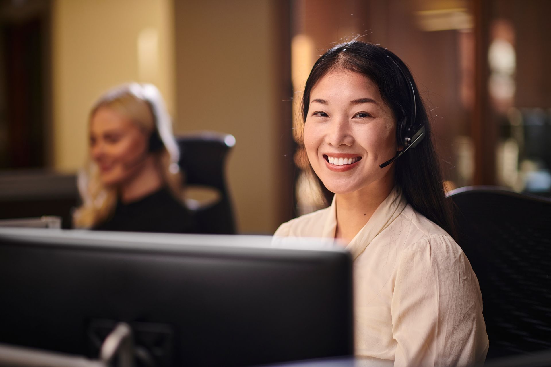 Smiling Filipina customer service agent wearing a headset at her workstation in a Philippine BPO office