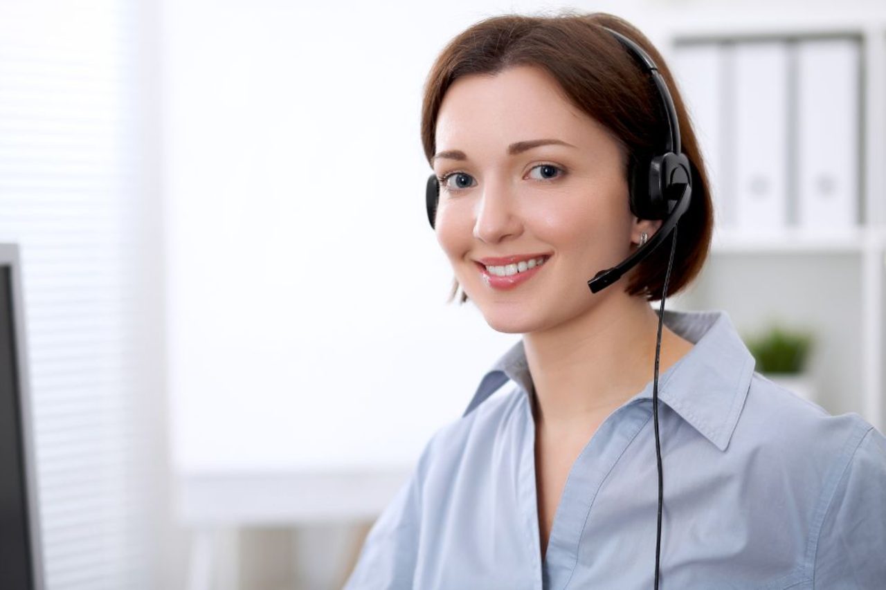 Smiling contact center agent in a headset at her desk in a bright Philippine BPO office