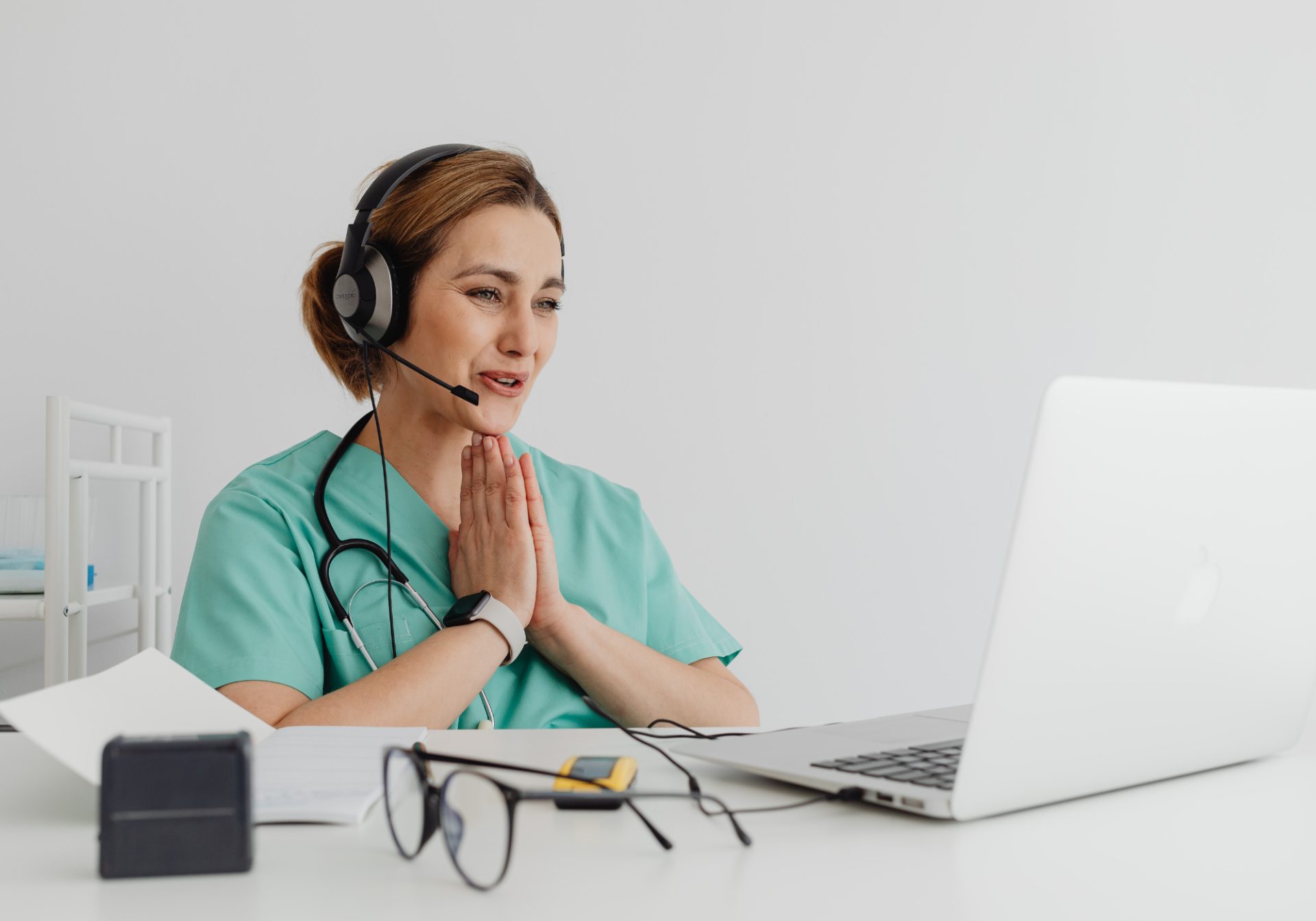 Healthcare support agent in scrubs with a headset talking a patient through a question on her laptop