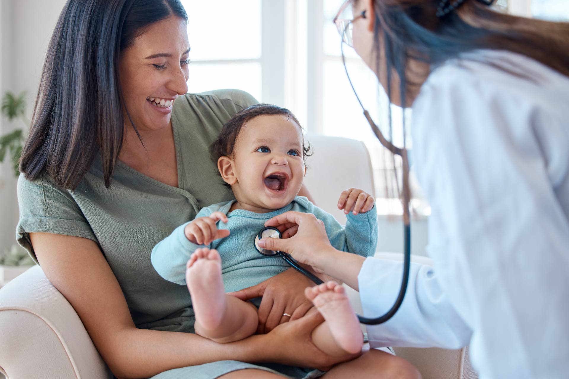 Pediatrician examining a smiling infant held by a parent, representing patient support delivered by Philippine healthcare BPO teams