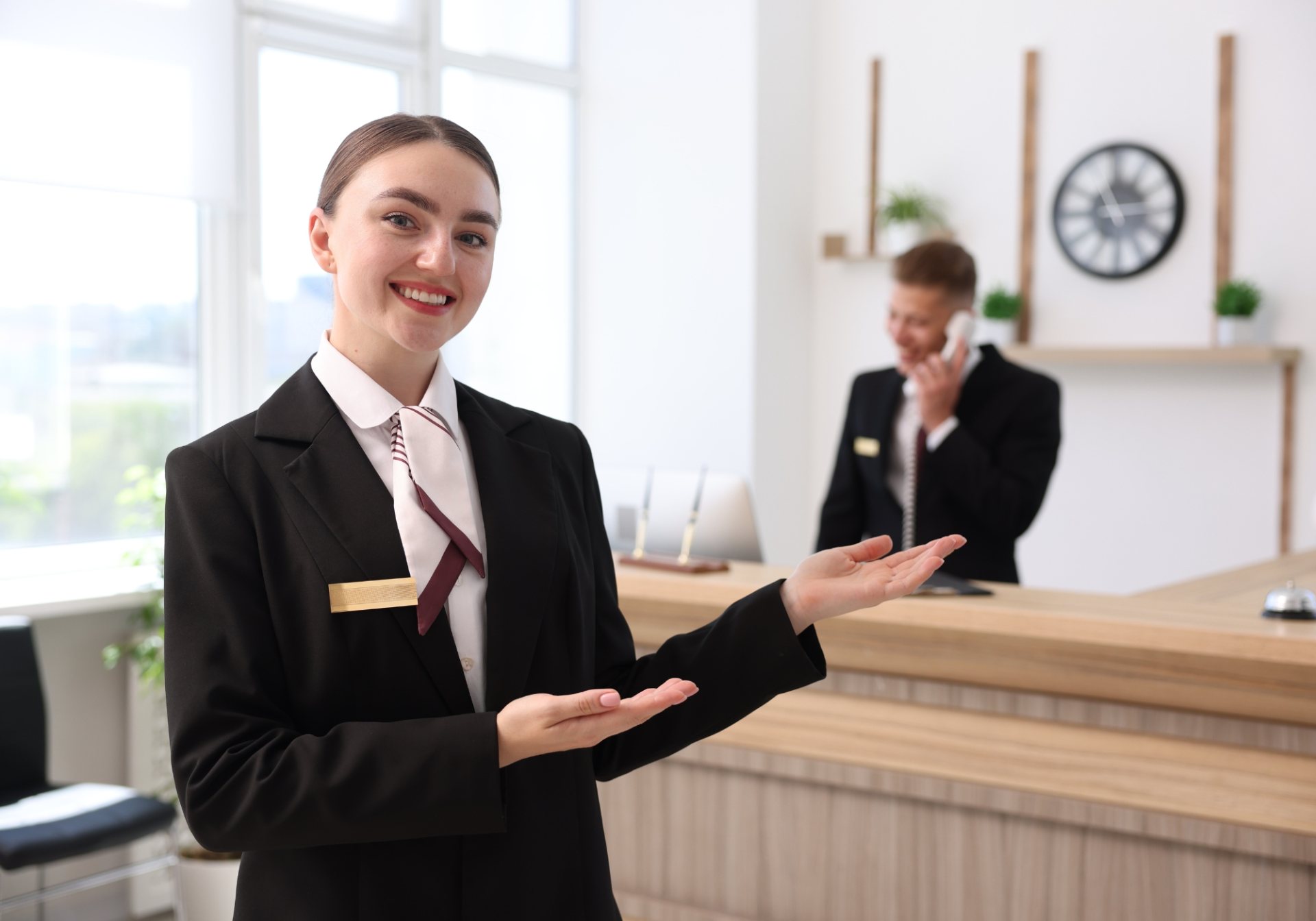 Smiling hotel receptionist welcoming guests at the front desk, where group and event bookings arrive