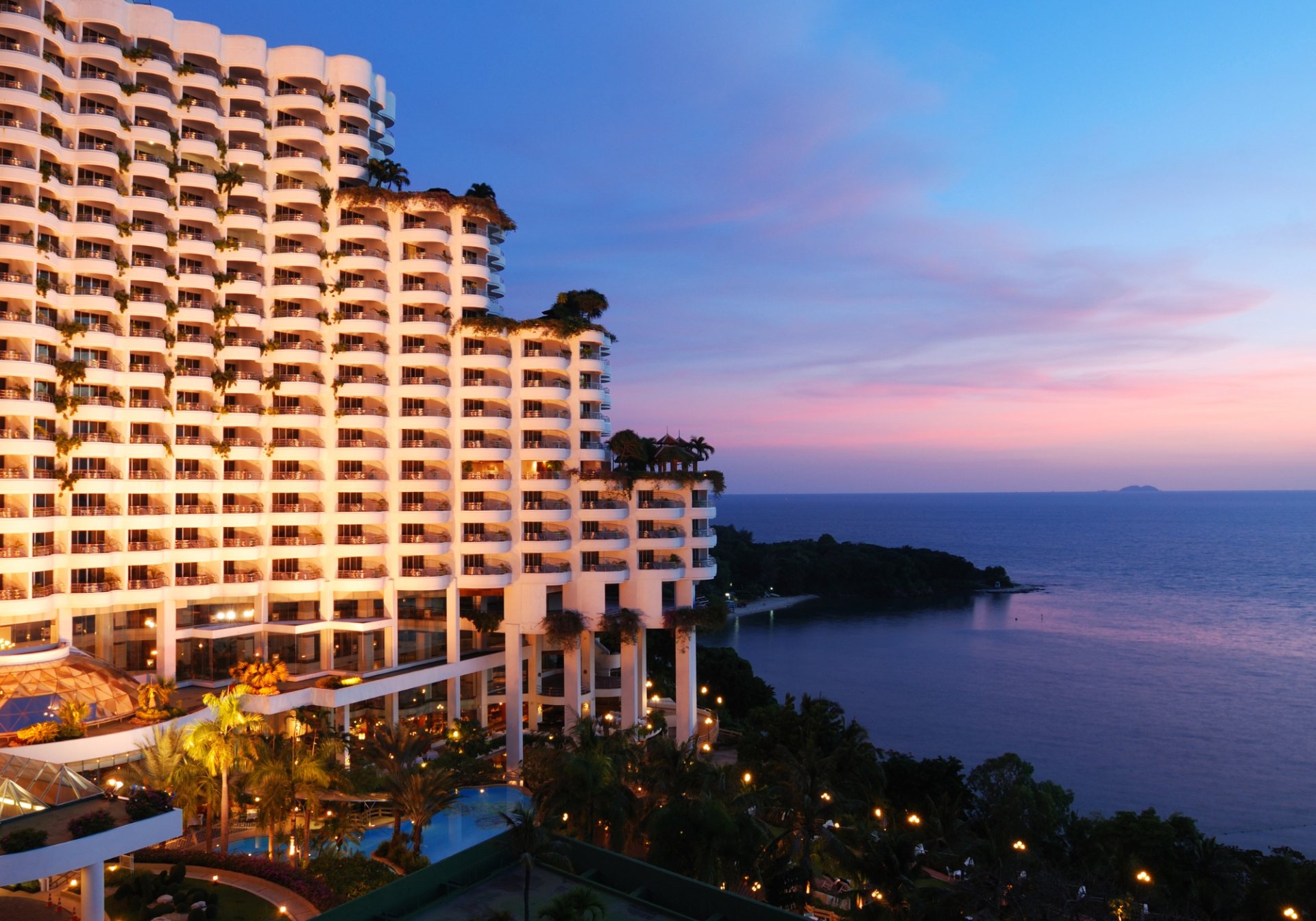 Seaside resort hotel lit up at dusk, for a post on channel manager overbooking