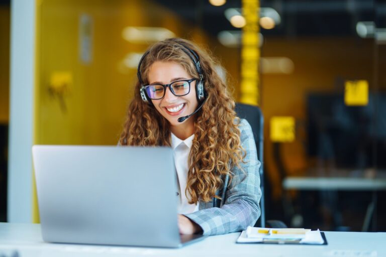 Reservations agent with a headset handling a booking on her laptop, for a post on travel disruption surge plan