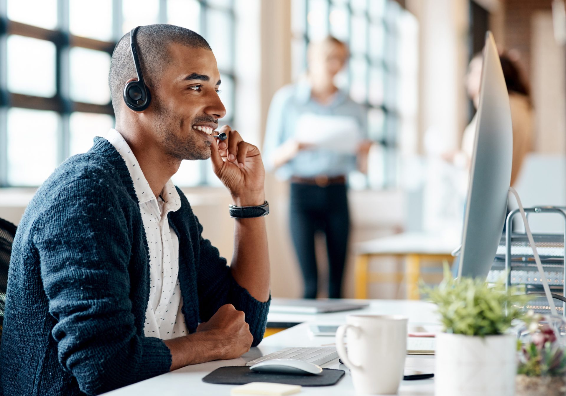 Smiling intake specialist with a headset at his desk, taking a new-case call, for a post on legal intake speed to lead