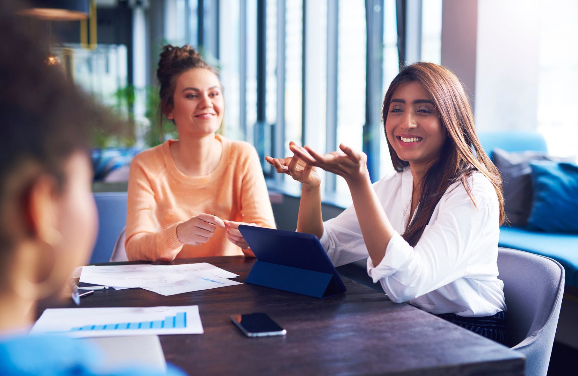 Smiling loyalty program advisor with a tablet talking with members at a table, representing loyalty and membership support from the Philippines