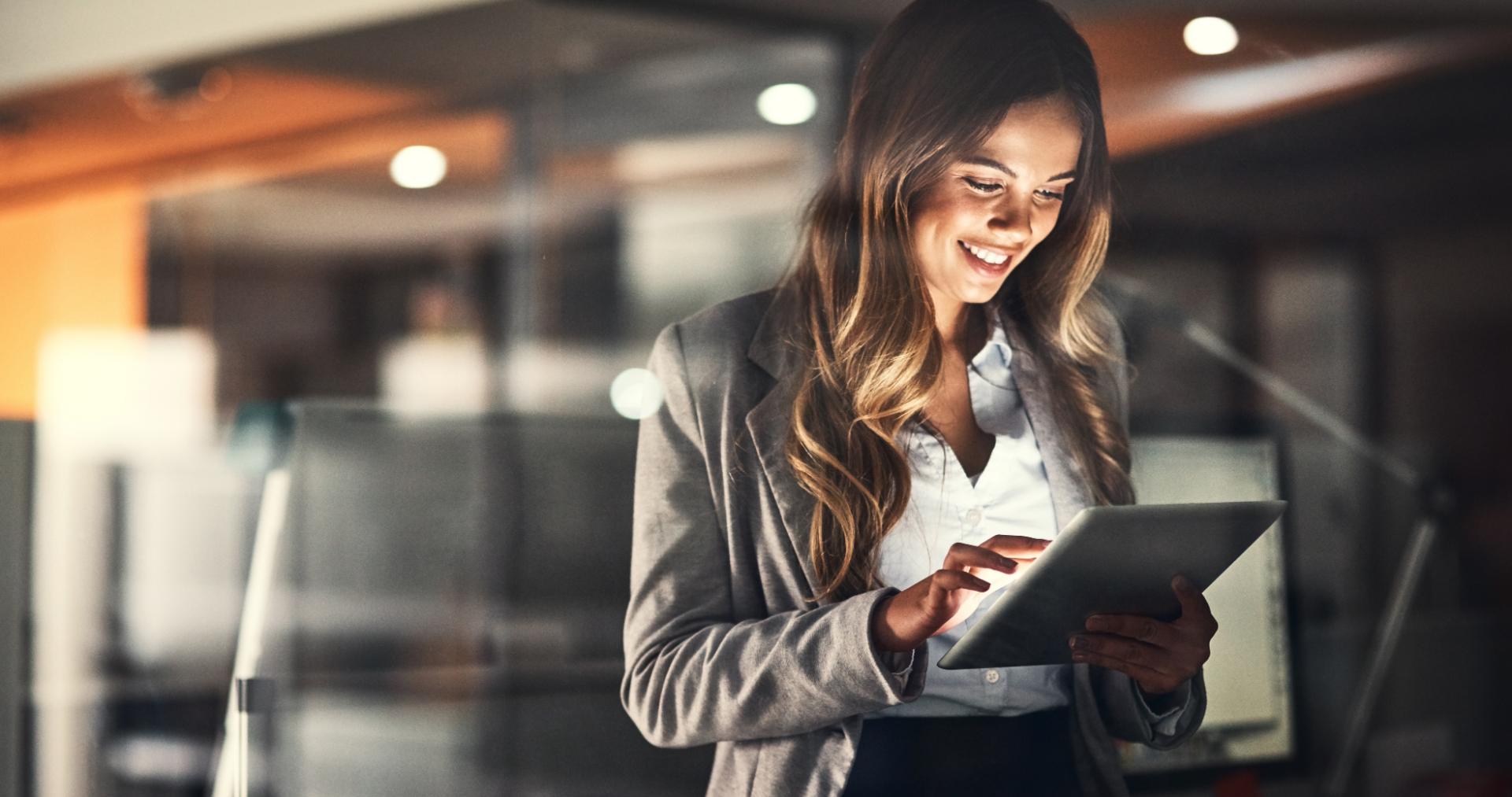 Business executive reviewing news coverage on a tablet in an office at night, representing PITON-Global's outsourcing commentary featured in the media and press