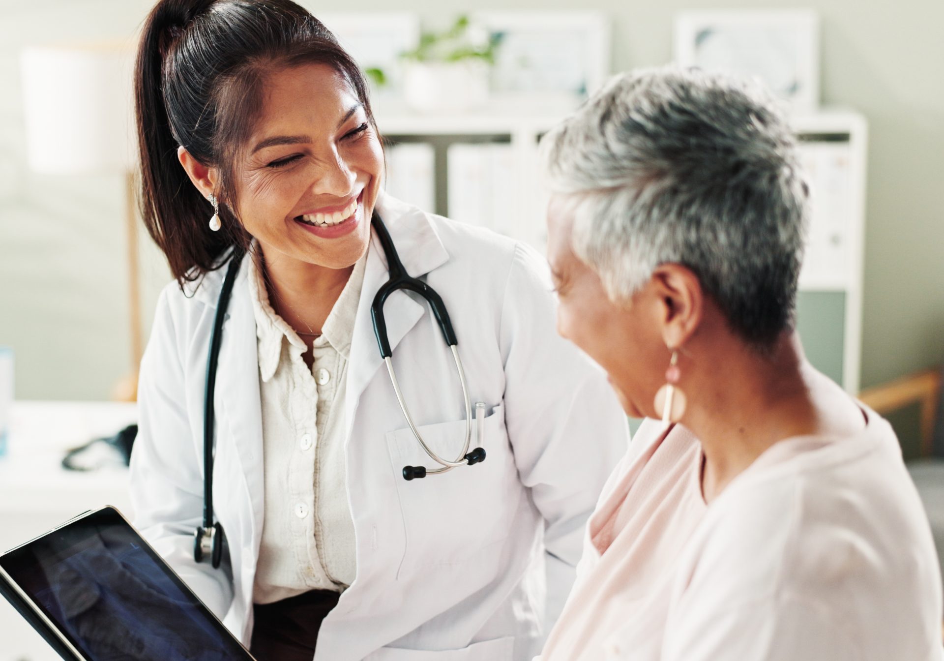 Doctor showing a scan on a tablet to a smiling older patient, the clinic side of connected medtech support