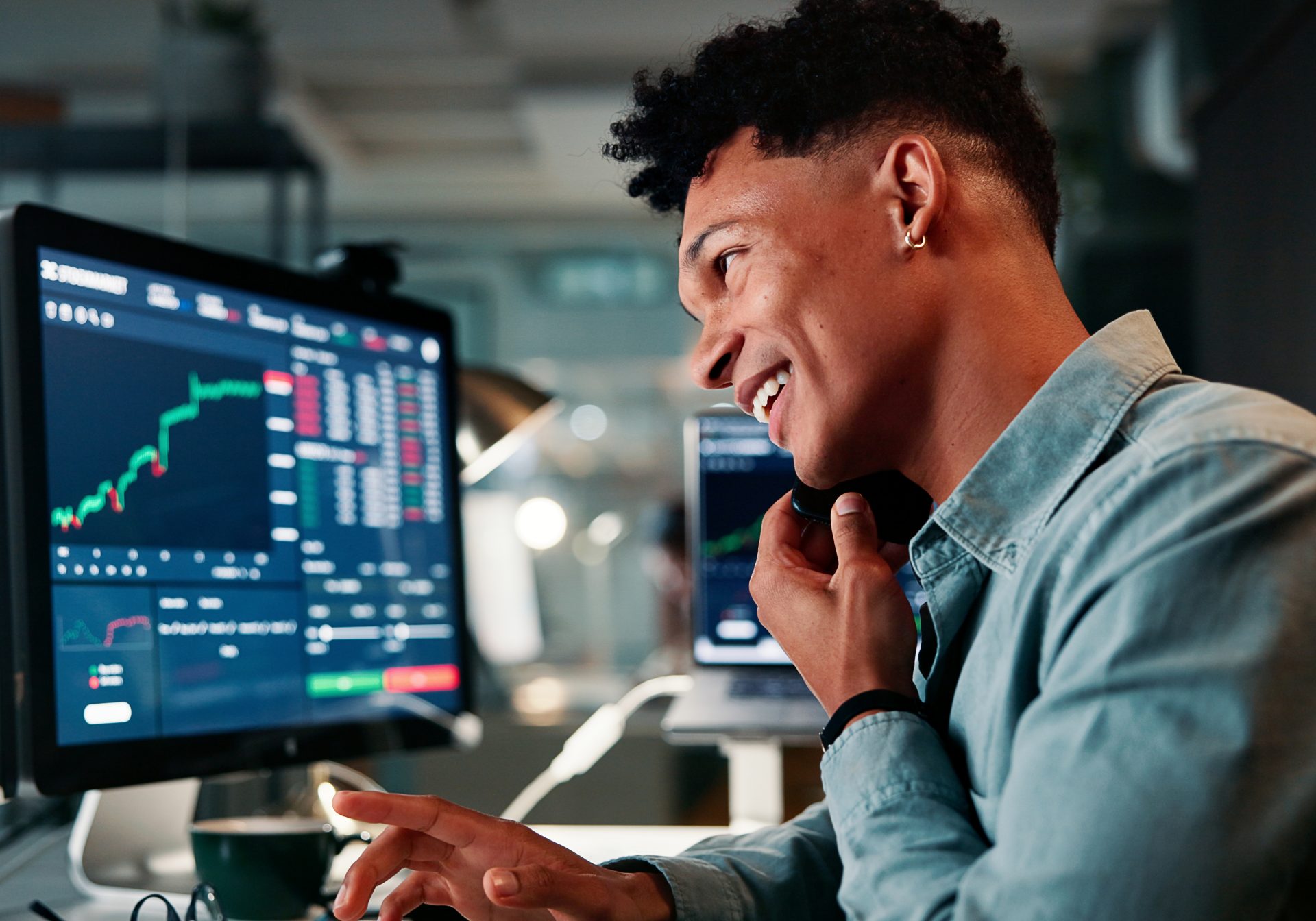 Smiling trader on the phone in front of live price charts, the kind of call prediction market support takes