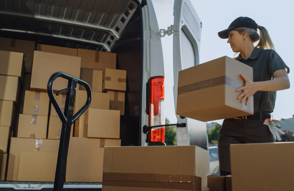Delivery worker loading parcels into a van beside a pallet jack, representing returns management and reverse logistics support from the Philippines